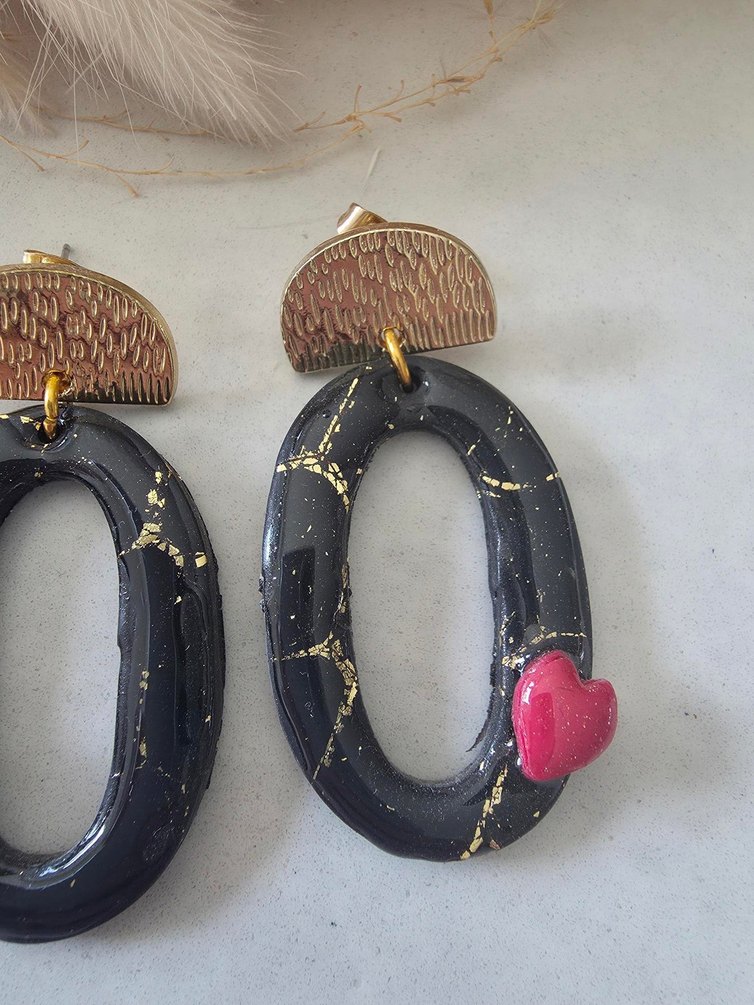 Boucles d'oreilles ovales en argile polymère – noir or & petit cœur rouge