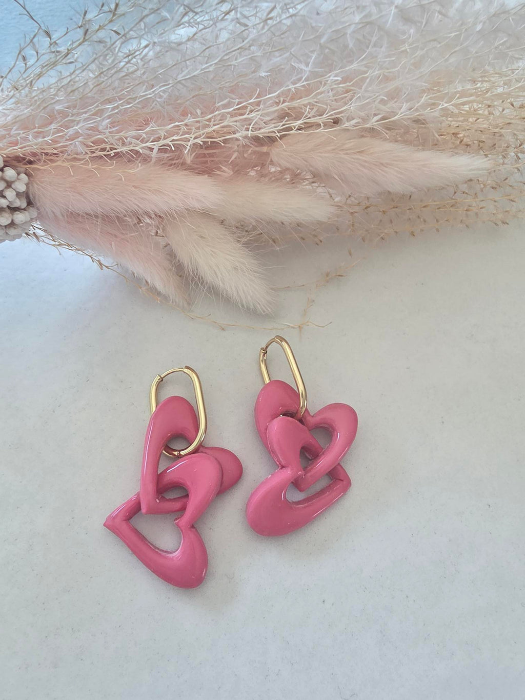 Boucles d'oreilles pendantes créole dorée – cœurs entrelacés en argile polymère rose (paire)