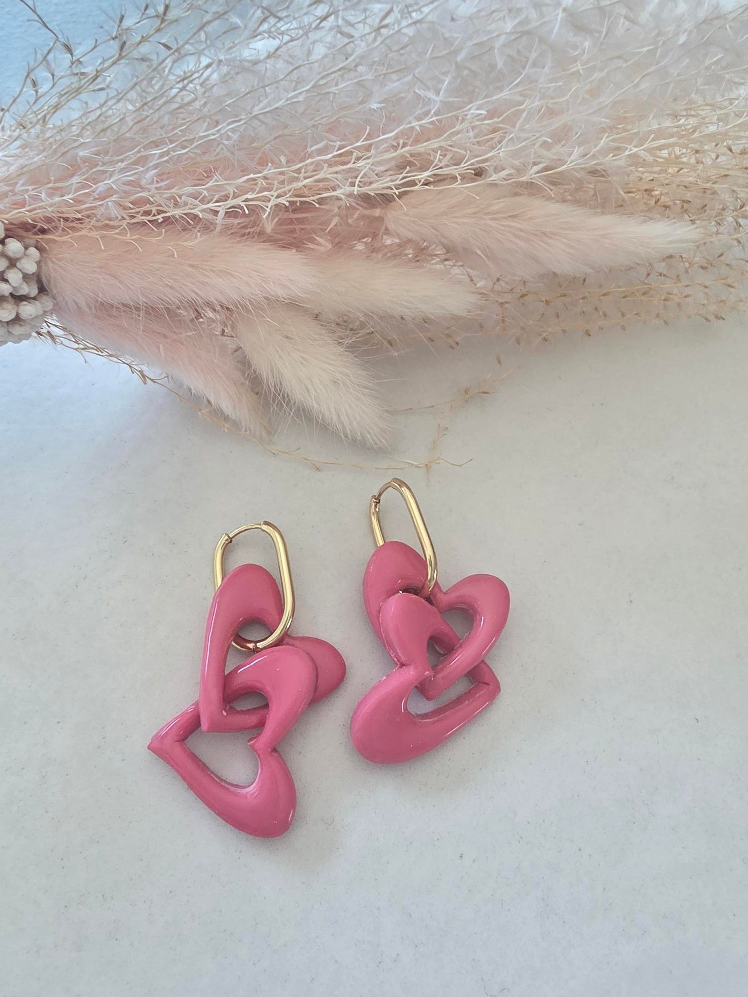 Boucles d'oreilles pendantes créole dorée – cœurs entrelacés en argile polymère rose (paire)